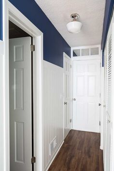 an empty hallway with blue walls and white trim on the doors, wood floors and hard wood flooring