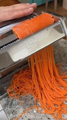 someone is grating carrots into a pasta machine