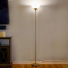 a living room with a lamp on the floor and a television mounted to the wall