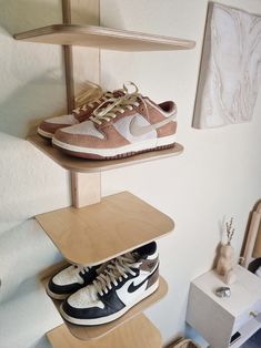 there are three shelves with shoes on top of each shelf, and one is holding two pairs of sneakers