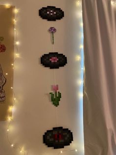 the pixel art is hanging on the wall next to some string lights and paper flowers