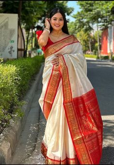 a woman in a red and white sari is talking on her cell phone while walking down the street