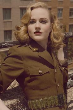 a woman in uniform is posing for a photo on a balcony with her hands behind her head