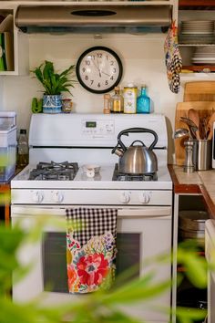 a white stove top oven sitting inside of a kitchen next to a microwave and pot holder