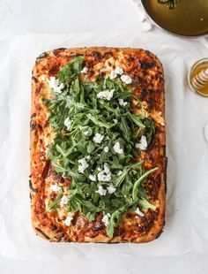 a square pizza topped with spinach and feta cheese on top of a table