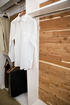 a white shirt hanging on a clothes rack next to a wooden wall and coat hanger