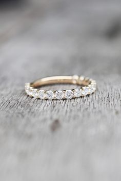 a gold wedding band with small diamonds on it sitting on top of a wooden table