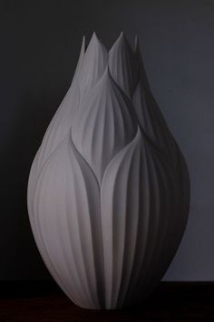 a white vase sitting on top of a wooden table