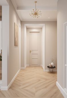 an empty hallway with a chandelier and wooden flooring is shown in this image