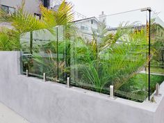 an outdoor garden with plants and fenced in area next to it on the side of a building