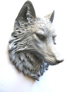 a statue of a wolf's head on a white wall