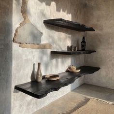 three shelves with vases and plates on them in a room that looks like it has been made out of concrete