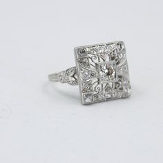 Platinum Edwardian diamond ring. Beautiful filigree and engraved square mounting. Old cut center stone .45 carat surrounded by single cuts. The corners have table cut stones . ~1.25 carat total weight. Size 7 3/4 Ring is of style that may be sized by a jeweler. 0.20 Oz total weight of ring Jewelers Appraisal available upon request. This item is vintage. It has been cherished, worn, and preserved by possibly many over the decades of its unique existence. Noted signs of age and restoration: One si Edwardian Diamond Ring, Diamond Ring Platinum, Antique Diamond Ring, Unique Rings Vintage, Ring Square, Vintage Cocktail Ring, Diamond Cocktail Ring, Square Ring, Antique Ring