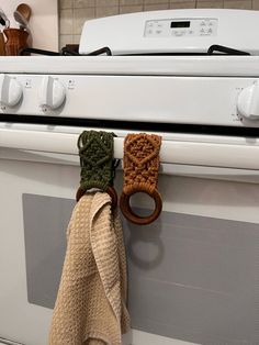 two wooden rings are hanging from the handle of an oven door knob on a white stove