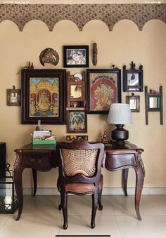 two chairs sitting in front of a desk with pictures on the wall above it and a lamp