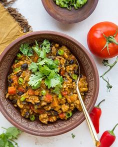 two bowls filled with food next to tomatoes