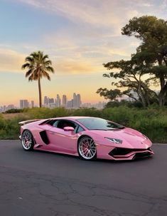 a pink lamb car parked on the street in front of some palm trees and buildings