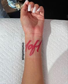 a woman's arm with a red and white tattoo on her left wrist that says off