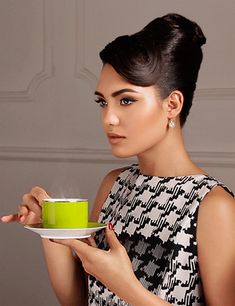 a woman holding a green cup and saucer