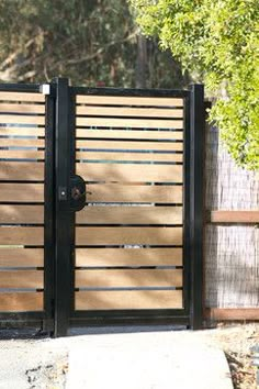 an open gate with wooden slats on the top and bottom, in front of a tree