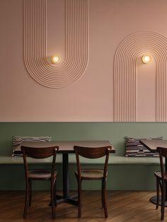 two wooden tables and chairs in front of a pink wall