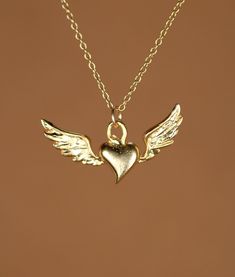 Flying heart necklace, silver heart pendant with wings, wing necklace, a 14k gold vermeil heart and wings on a 14k gold filled chain This super cute and dainty 14k gold plated sterling silver flying heart hangs from a 14k gold filled chain in the length of your choice! This beauty is also available in sterling silver and the pendant measures 22mm x 8mm. Looking for other charm necklaces? https://www.etsy.com/shop/BubuRuby?section_id=12318467 More crystals and healers? http://www.etsy.com/shop/Bu Gold Winged Sterling Silver Jewelry, Gold Wing-shaped Sterling Silver Necklace, Heart-shaped Angel Wings Jewelry Gift, Sterling Silver Heart Jewelry With Angel Wings, Sterling Silver Gold Angel Wings Jewelry, Gold Sterling Silver Jewelry With Angel Wings, Elegant Heart-shaped Angel Wings Necklace, Elegant Heart Shaped Angel Wings Necklace, Angel Wings Heart Pendant Jewelry For Gifts