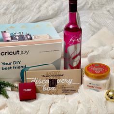 a bottle of wine sitting next to other items on a white blanket with christmas decorations