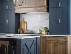 a kitchen with blue cabinets and white marble counter tops, an island in the middle