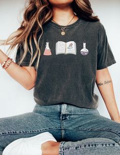 a woman sitting on the floor with her legs crossed wearing jeans and a t - shirt