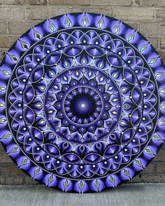 a purple and black circular artwork on the side of a brick wall