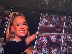 a woman is smiling while standing in front of a large screen at a sporting event