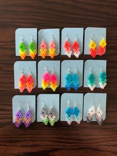 six pairs of earrings made out of plastic beads on top of a wooden table next to each other