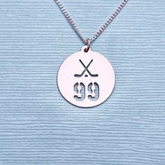 a necklace with two crossed sticks and the number 99 on it, hanging from a silver ball chain