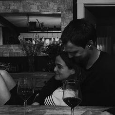 a man and woman sitting at a table with wine glasses