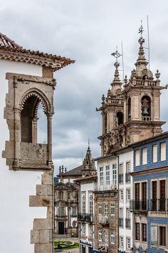 an old building with two bell towers on top and other buildings in the back ground