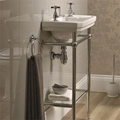 a white sink sitting next to a bath tub in a bathroom on top of a hard wood floor