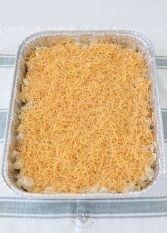 an uncooked casserole dish with cheese in it on a tablecloth