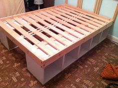 a wooden bed frame sitting on top of a hard wood floor next to a wall