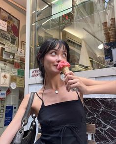 a woman eating an ice cream cone in front of a store