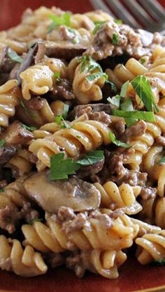 a close up of a plate of food with pasta and meat on it next to a fork