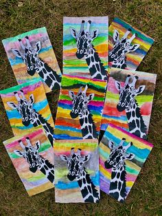 four giraffes are painted on colorful paper and placed in the grass together