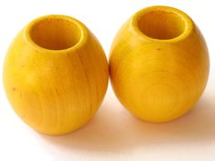 two yellow wooden vases sitting on top of a white table next to each other