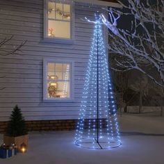 a lighted christmas tree in front of a house