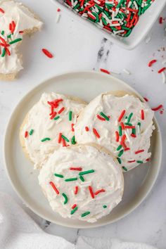 white frosted cookies with sprinkles on a plate next to a baking dish