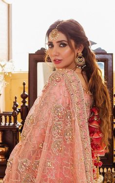 a woman in a pink lehenga with gold jewelry on her head and long hair