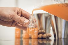 a person is pouring orange juice into a glass bottle with the word happy buddha on it