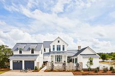 a large white house with two garages and a bicycle parked in front of it