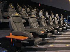 rows of seats in an empty auditorium with yellow arrows on the floor and black walls