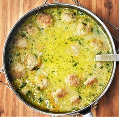 a pan filled with meatballs and gravy on top of a wooden table