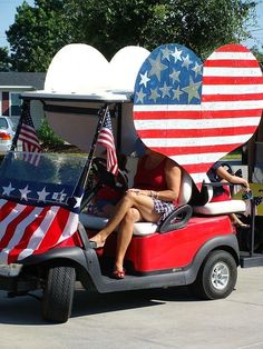 two women are riding in a golf cart decorated with american flags and hearts on the back